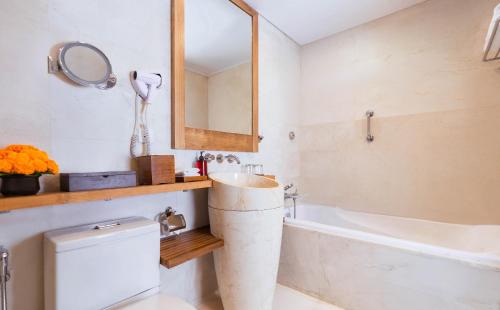 a bathroom with a tub and a sink and a toilet at Legian Beach Hotel in Legian