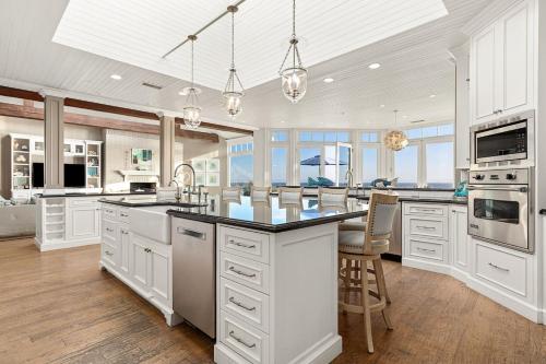 a large kitchen with white cabinets and a large island at Malibu Dunes by Fieldtrip Expansive Hamptons-Style Estate w Private Beach Backyard in Malibu