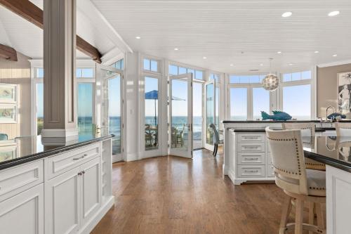 a kitchen with white cabinets and glass windows at Malibu Dunes by Fieldtrip Expansive Hamptons-Style Estate w Private Beach Backyard in Malibu