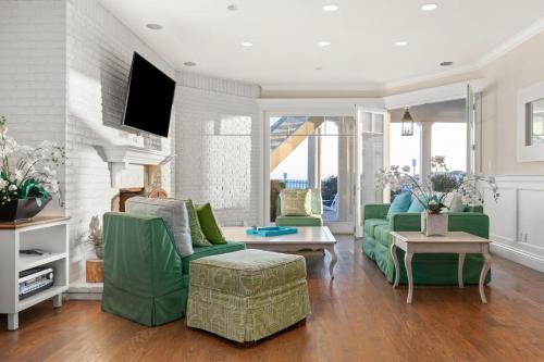 a living room with green couches and a tv at Malibu Dunes by Fieldtrip Expansive Hamptons-Style Estate w Private Beach Backyard in Malibu