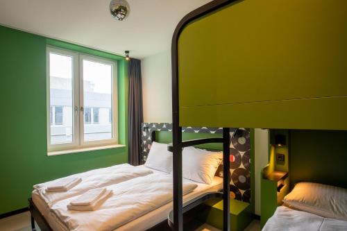 a green bedroom with a bed and a window at MEININGER Hotel Dresden Zentrum in Dresden