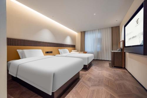 two beds in a hotel room with a flat screen tv at Yi Nian · Fangcun Hotel in Nanchang
