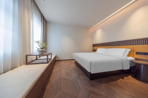 a bedroom with a white bed and a window at Yi Nian · Fangcun Hotel in Nanchang