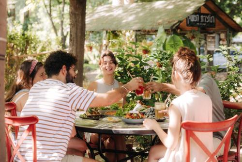 a group of people sitting around a table eating food at Vitrage Holiday Village and Spa in Bet Hillel