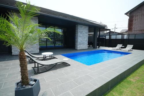 a patio with a pool and chairs and a palm tree at LAKE villa CHITOSE in Hikone