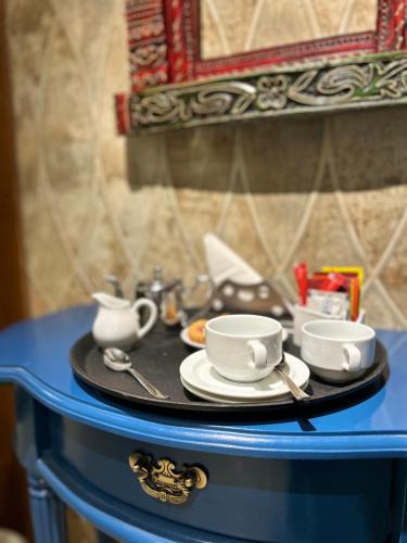 a tray with cups and saucers on a blue table at Vaydantaa - Luxury Boutique Resort Mussoorie in Mussoorie