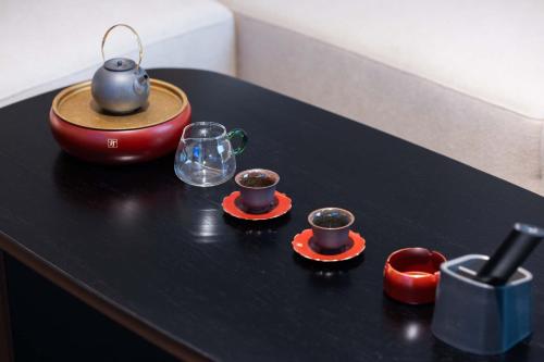 a black table with two cups and a tea pot at Yi Nian · Fangcun Hotel in Nanchang