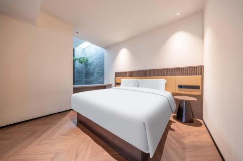 a bedroom with a large white bed and a window at Yi Nian · Fangcun Hotel in Nanchang
