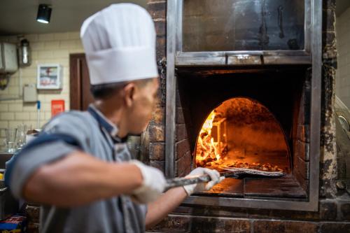 a man putting a pizza into an oven at Novotel Bogor Golf Resort in Bogor