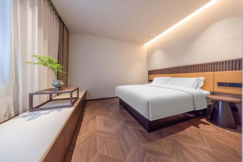 a bedroom with a white bed and a table at Yi Nian · Fangcun Hotel in Nanchang