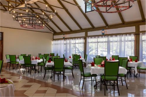 a dining room with white tables and green chairs at Naivasha Crescent Lodge in Naivasha