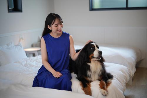 a young girl sitting on a bed with a dog at LAKE villa CHITOSE in Hikone