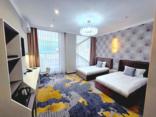a hotel room with two beds and a chandelier at Palmira Hotel Bishkek in Bishkek