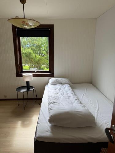 a bedroom with a white bed and a window at Sunde Fjord view, easy and cheap! in Sula