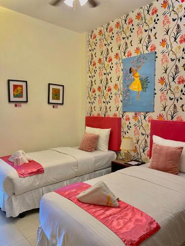 two beds in a room with red and white sheets at Balai Carmela in Tuguegarao City