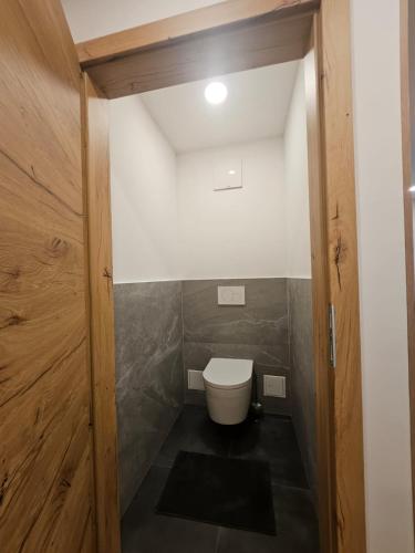 a small bathroom with a toilet and a wooden door at Gasthaus Eichholzer in Murau
