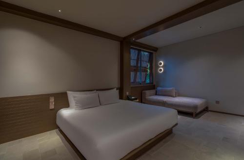 a bedroom with a large white bed and a chair at Harvest Day Hoi An in Hoi An