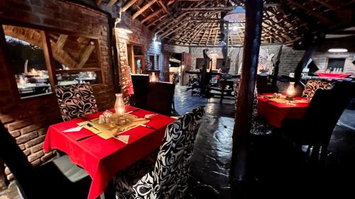 a restaurant with two tables with red table cloth at Roy's Rest Camp in Groutfontein