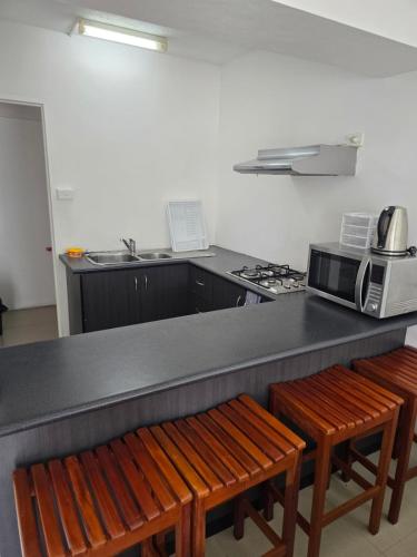 a kitchen with a counter with two wooden chairs and a microwave at Island Accommodation Suva Premier Hospitality in Suva