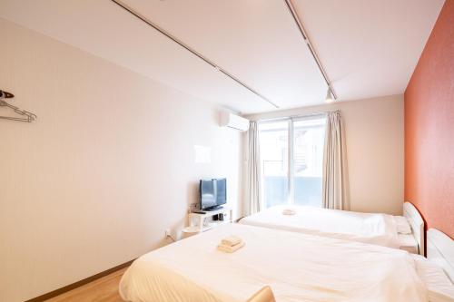 a bedroom with two beds and a window at 難波民泊301 in Osaka