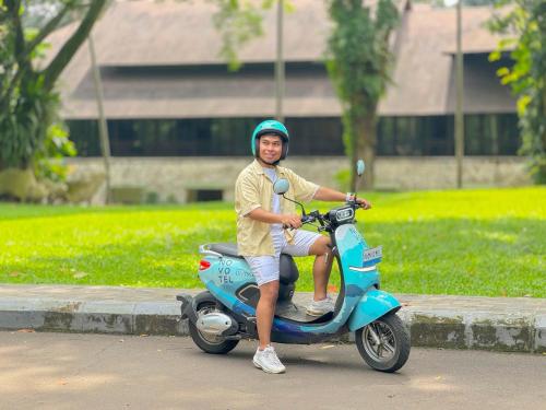 a man is sitting on a scooter on the street at Novotel Bogor Golf Resort in Bogor