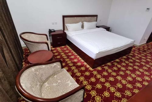 a bedroom with a bed and a chair and a table at Kohi Afsaron in Dushanbe