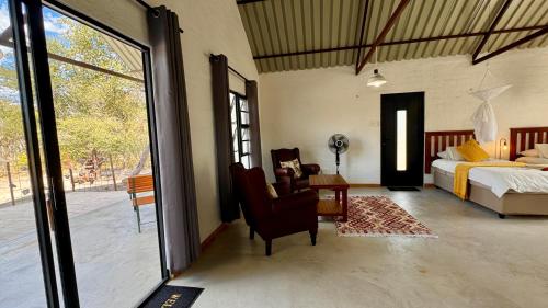 a bedroom with a bed and a bed and a chair at Roy's Rest Camp in Groutfontein