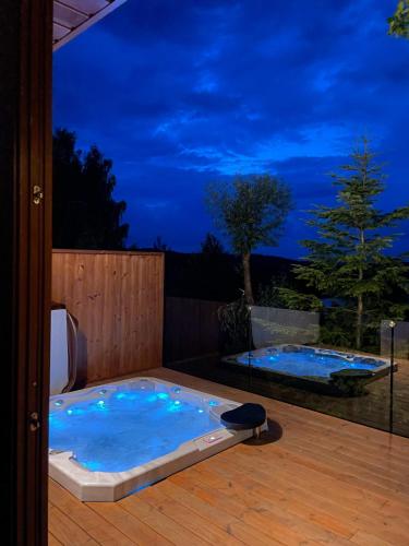 two hot tubs on a deck at night at Zloty, a Skromny - ogrodzony domek z jacuzzi i widokiem na jezioro in Górzno