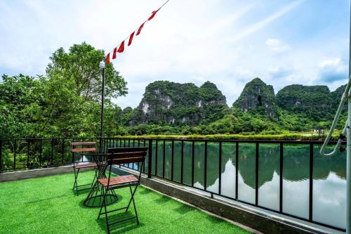 two chairs and a table on a balcony overlooking a body of water at Tràng An Sunny River Homestay in Ninh Binh
