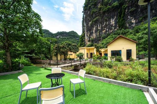 a patio with chairs and a table on a lawn at Tràng An Sunny River Homestay in Ninh Binh
