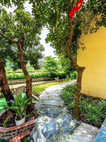 a garden with trees and a stone path at Tràng An Sunny River Homestay in Ninh Binh