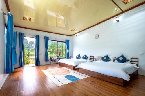 two beds in a bedroom with blue curtains at Tràng An Sunny River Homestay in Ninh Binh