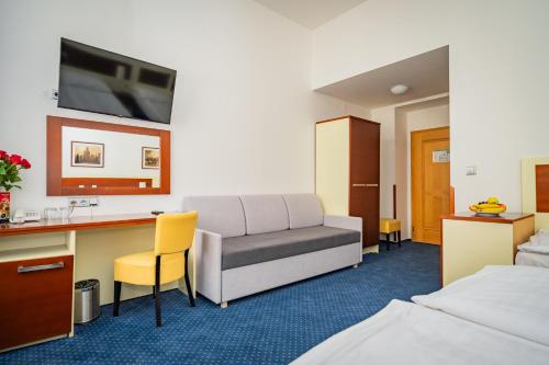 a hotel room with a couch and a desk at Hotel Atos in Prague