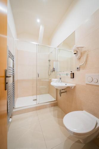 a bathroom with a shower and a toilet and a sink at Hotel Atos in Prague