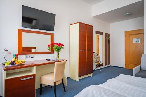 a hotel room with a desk and a bed at Hotel Atos in Prague