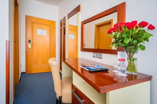 a bathroom with a vase of red flowers on a counter at Hotel Atos in Prague