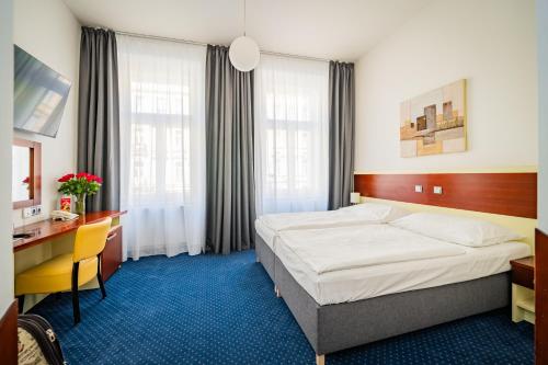 a hotel room with a bed and a desk at Hotel Atos in Prague