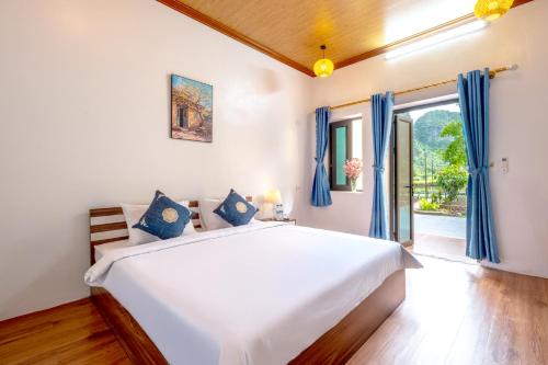 a bedroom with a large white bed with blue curtains at Tràng An Sunny River Homestay in Ninh Binh