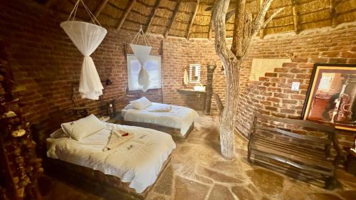 a bedroom with two beds and a tree in it at Roy's Rest Camp in Groutfontein