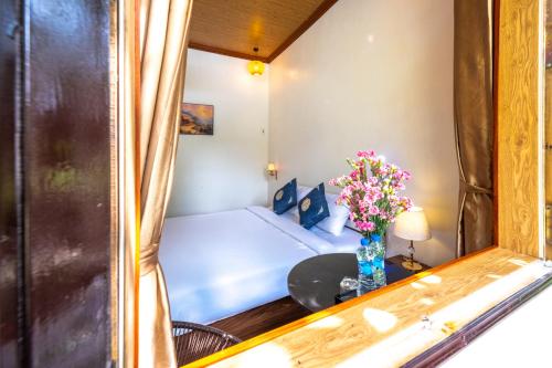 a room with a bed and a table with a vase of flowers at Tràng An Sunny River Homestay in Ninh Binh