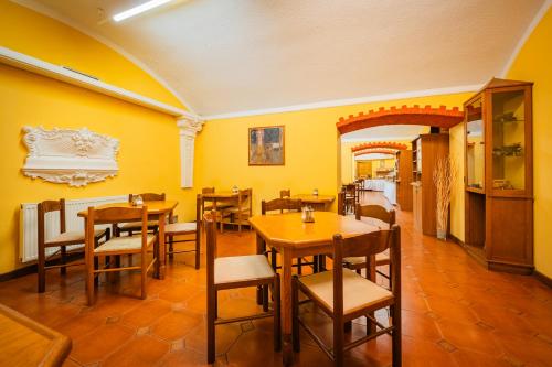 a restaurant with yellow walls and wooden tables and chairs at Hotel Atos in Prague