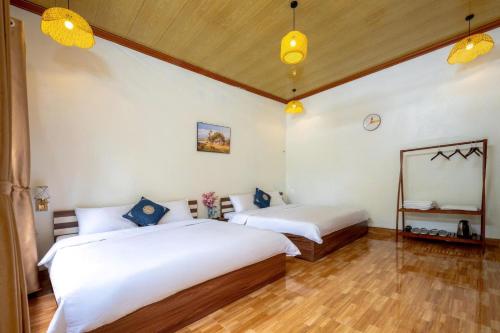 two beds in a room with white walls and wooden floors at Tràng An Sunny River Homestay in Ninh Binh