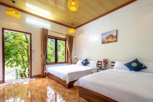 two beds in a room with two windows at Tràng An Sunny River Homestay in Ninh Binh