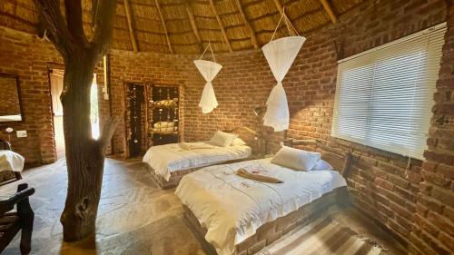 a bedroom with two beds in a brick wall at Roy's Rest Camp in Groutfontein