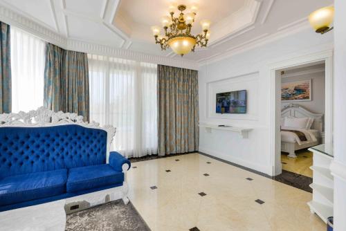 a living room with a blue couch and a bed at Lan Rung Beach Resort in Long Hai