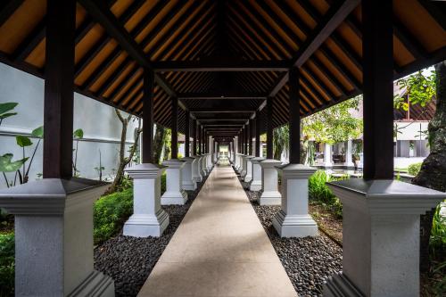 a long walkway with columns and a wooden ceiling at Novotel Bogor Golf Resort in Bogor