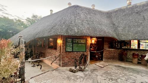a small brick building with a thatched roof at Roy's Rest Camp in Groutfontein
