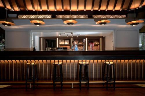 a woman standing behind a bar with three bar stools at Novotel Bogor Golf Resort in Bogor