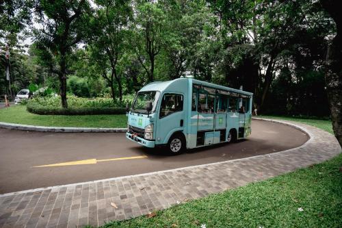 a blue bus is driving down a road at Novotel Bogor Golf Resort in Bogor