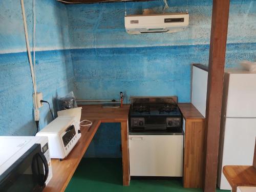 a small kitchen with a stove and a refrigerator at Unwind DAY OFF Nagamo in Yaese